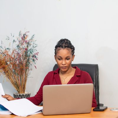 Young African woman is working at a table in a modern office setting.